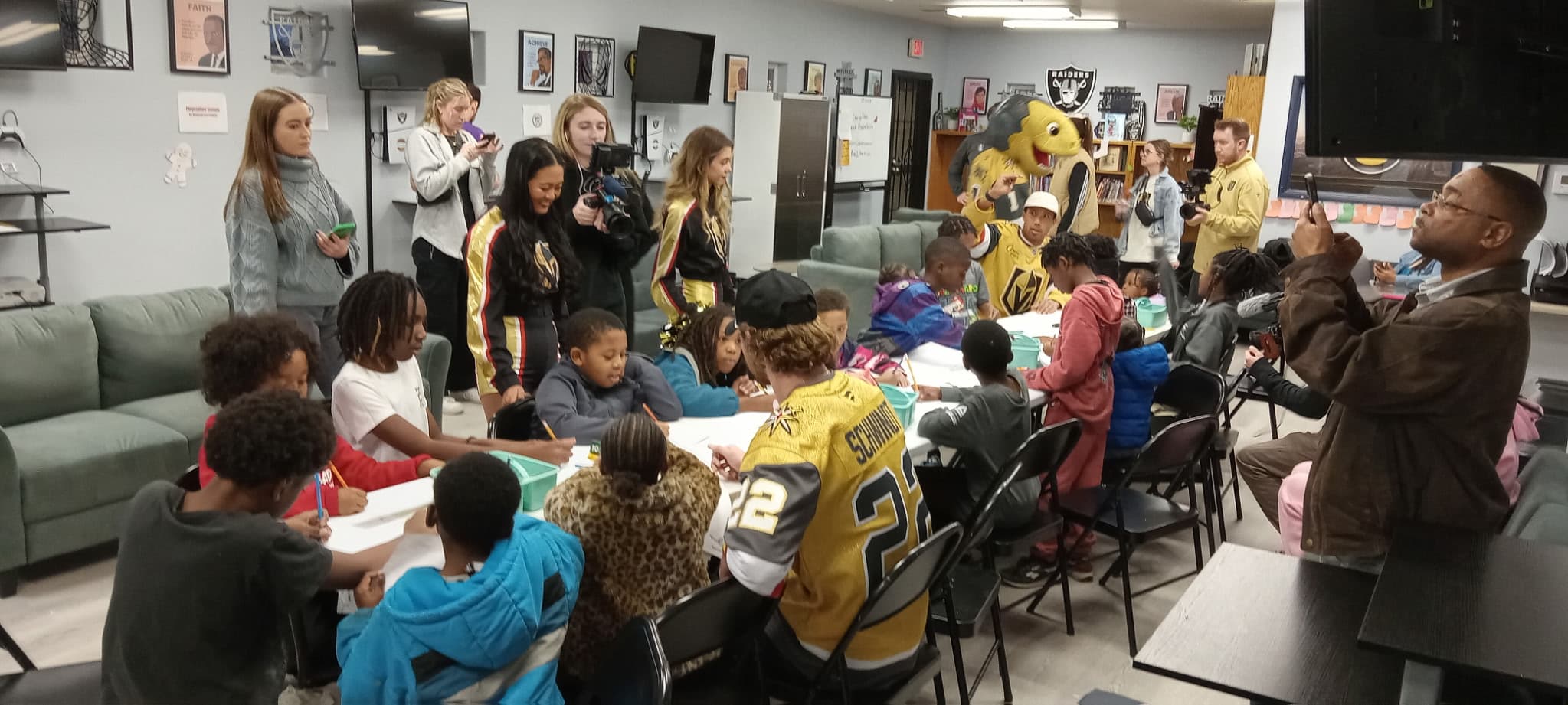 Children and Vegas Golden Knights players interact with a mascot at a community event table.